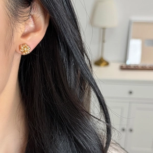 Elegant gold floral stud earrings with sparkling crystals and pearls on model