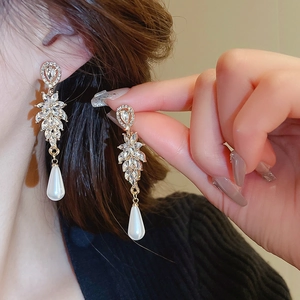 Close-up of model wearing leaf-shaped crystal earrings with teardrop pearls