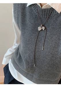 Detail of a textured silver double heart pendant on a long dark necklace cord