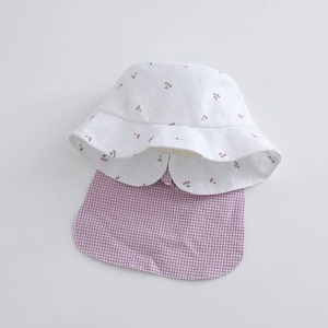 Close-up of white hollow embroidery fabric with cherry prints and pink plaid neck flap