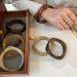 Irregular resin bangle with amber marble pattern shown in a retro jewelry display box