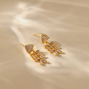 Detailed close-up of leaf-shaped fishbone earrings with 18K gold plating and zircon crystals