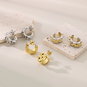 Detail of C-shaped textured hoop earrings in gold and silver on stone stands