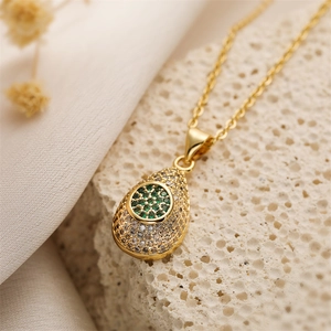 Détail macro du collier goutte plaqué or avec pierres vertes et zircons blancs