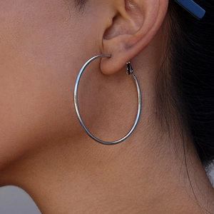 Close-up of a large silver stainless steel hoop earring worn by a model on left ear