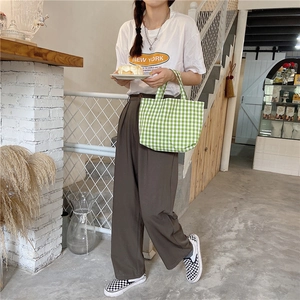 Green and white plaid cotton linen tote bag held by a model in a casual setting