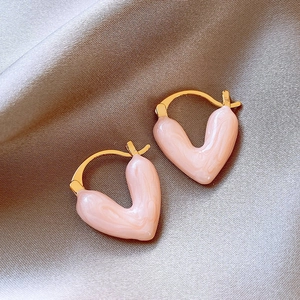 Detailed close-up of vintage pink heart enamel earrings on a grey silk fabric background