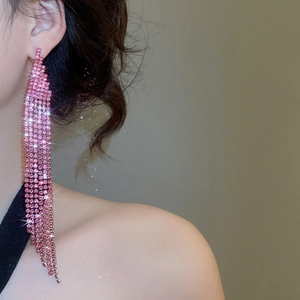 Detailed view of long pink rhinestone fringe earrings worn by a model in close-up