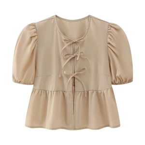 Detail of beige puff sleeve blouse with ribbon bow closures and ruffled hemline