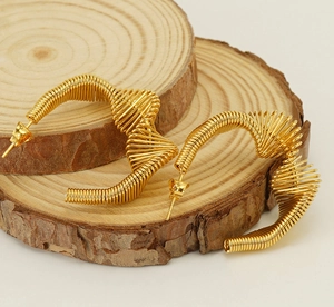 Macro shot of gold spiral wire earrings on natural wood blocks showing metal texture