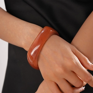 Close-up of a wide amber resin geometric round bangle on a model's wrist with high gloss
