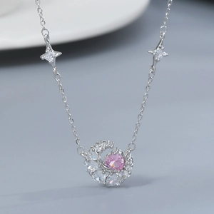 Macro detail of silver moon pendant featuring pink heart gem and pavé cubic zirconia
