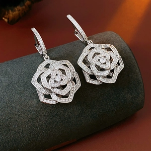 Macro detail of silver flower earrings with clear zircon stones on a textured stand