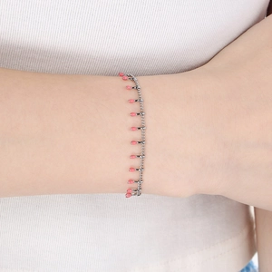 Close-up of a silver link bracelet with pink enamel matchstick charms on a wrist
