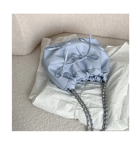 Detailed view of light blue soft PU leather handbag with pleats and cute bow accents