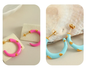 Detailed macro view of pink and blue enamel C-shaped earrings with gold heart accents