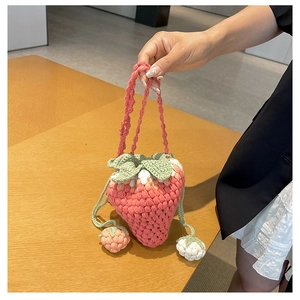 Detail of handmade knit strawberry bucket bag with drawstring closure and green leaf accents