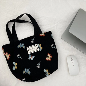 Borsa in tela con ricami a farfalla ed etichetta "PLEASANT TIME" su sfondo bianco
