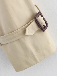Detail of beige trench coat cuff featuring high-quality twill fabric and brown buckle