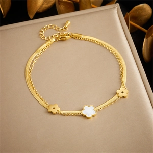 Detail of layered gold stainless steel anklet with white shell flower charms and snake chain