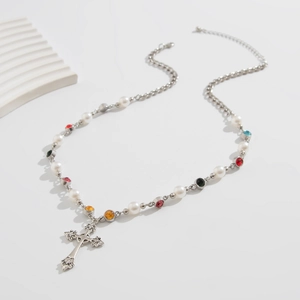 Detail of silver chain necklace with pearls, colorful gems and a cross pendant