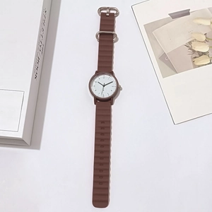 Detail of brown wavy silicone strap and white round dial on minimalist quartz watch