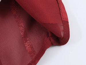 Detailed macro view of dark red mesh fabric with shimmering sequins and stripe texture