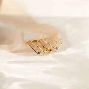 Detailed view of four V-shaped birthstone rings in gold, rose gold and silver finishes
