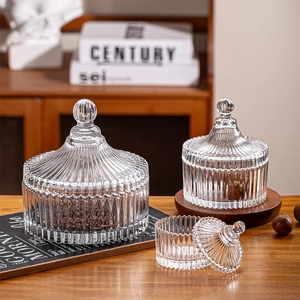 Close-up of three ribbed glass storage jars with lids on a warm wooden home table