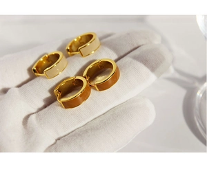 Detail of U-shaped gold earrings with cream white and caramel brown enamel inserts