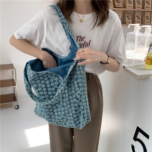 Detailed close-up of blue floral embroidery and lace texture on a canvas tote bag