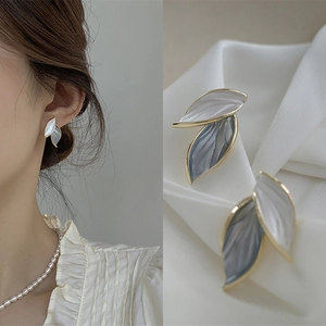 Detail of elegant leaf-shaped earrings with white and grey enamel on white silk