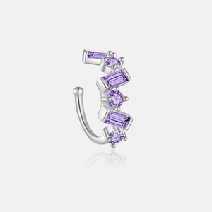 Macro shot of silver ear cuff with purple cubic zirconia on a reflective surface