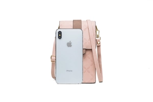 Size comparison of pink embossed mini crossbody phone bag next to a silver iPhone
