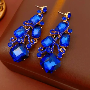 Close-up of vintage gold earrings with brilliant blue crystals on leather background