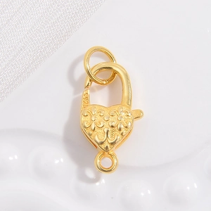 Macro detail of S925 sterling silver heart lobster clasp with floral engraving and gold finish