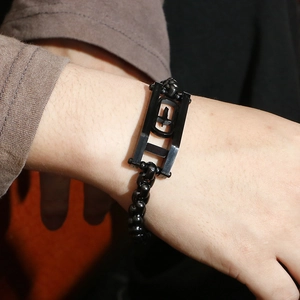 Detail of hip hop men's black beaded bracelet featuring geometric cross metal charms