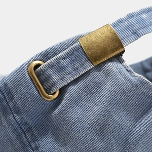 Detail of vintage denim baseball cap with adjustable bronze metal buckle and worn finish