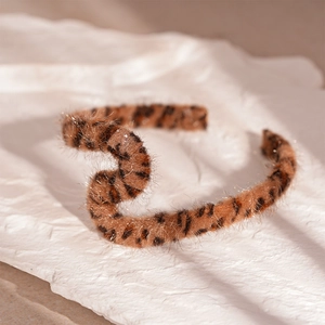 Close-up of vintage leopard print faux fur hair hoop with soft plush texture on white paper