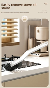 Detailed view of white ergonomic brush with stiff black bristles cleaning kitchen stovetop grime