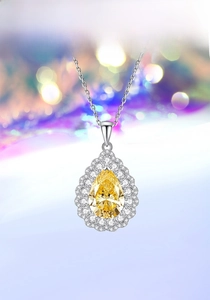 Macro detail of pear-cut yellow diamond pendant with double halo diamond setting
