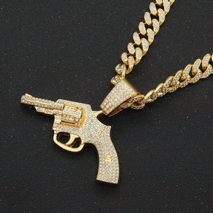 Macro shot of gold hip-hop Cuban chain with sparkling rhinestone-encrusted pistol pendant