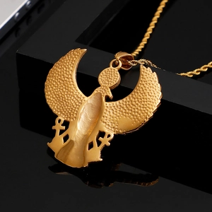 Macro detail of gold Egyptian Ankh sun bird pendant with rhinestones on black background