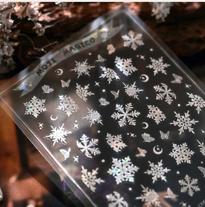 Macro detail of white 3D snowflake nail stickers with holographic shimmer on wood