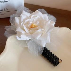 Détail d'une pince à cheveux fleur blanche avec pétales superposés et pince à spirale