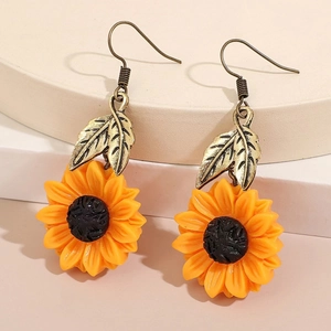 Detailed macro view of yellow lemon flower earrings with vintage bronze metal leaves
