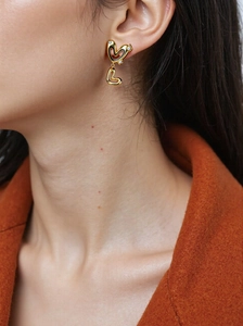 Close-up of model wearing gold double hollow heart drop earrings with crystal accents
