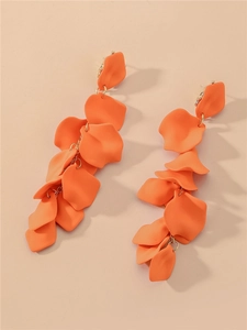 Détail de longues boucles d'oreilles à pompons en pétales de résine orange élégantes