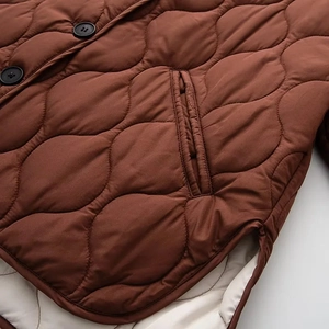 Détails de la veste matelassée marron avec poche latérale, boutons noirs et doublure douce