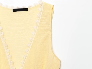 Detail shot of pale yellow ribbed tank top featuring delicate white lace trim on the neckline